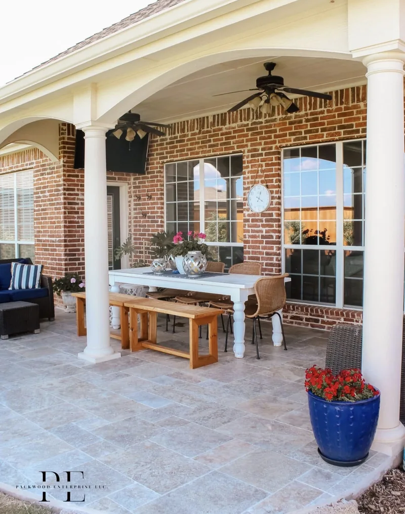 Covered patio with a dining table beside a brick home