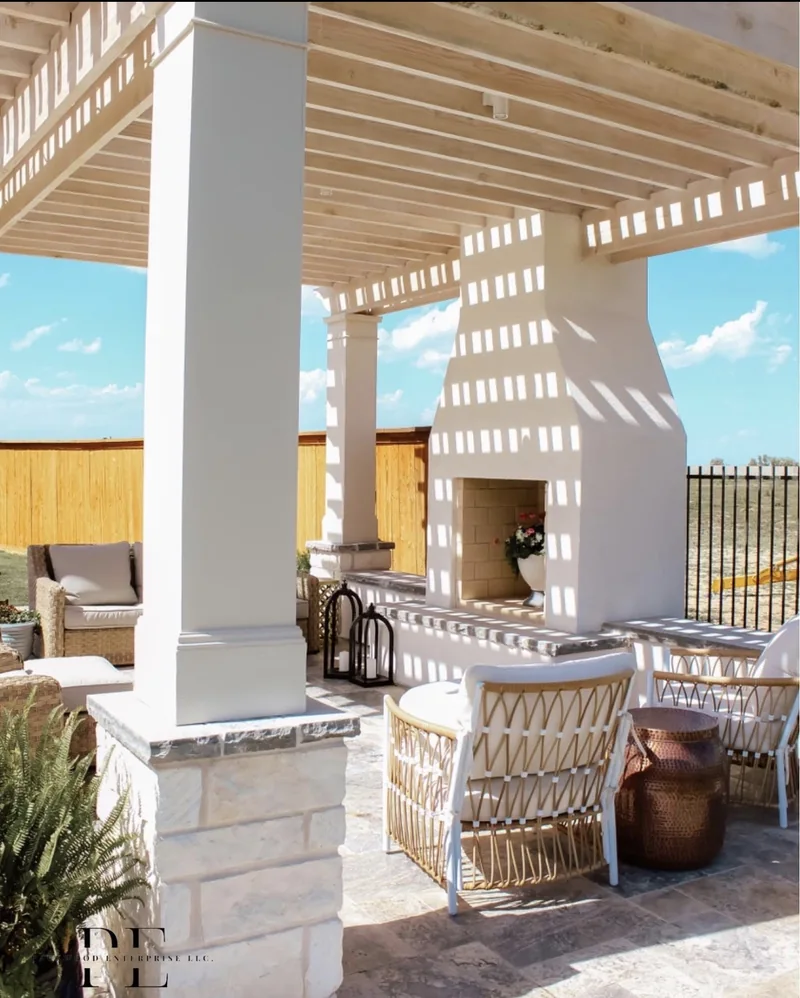 Pergola posts with stone bases beside an outdoor fireplace and seating