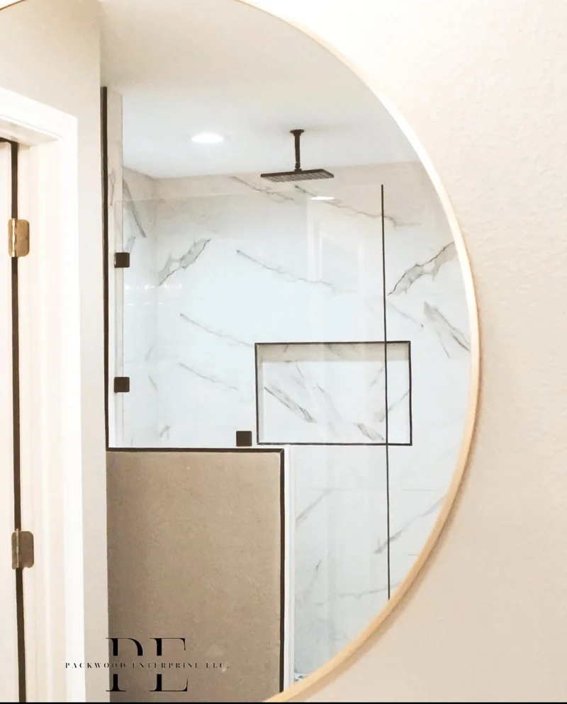 Round bathroom mirror reflecting a walk-in tile shower