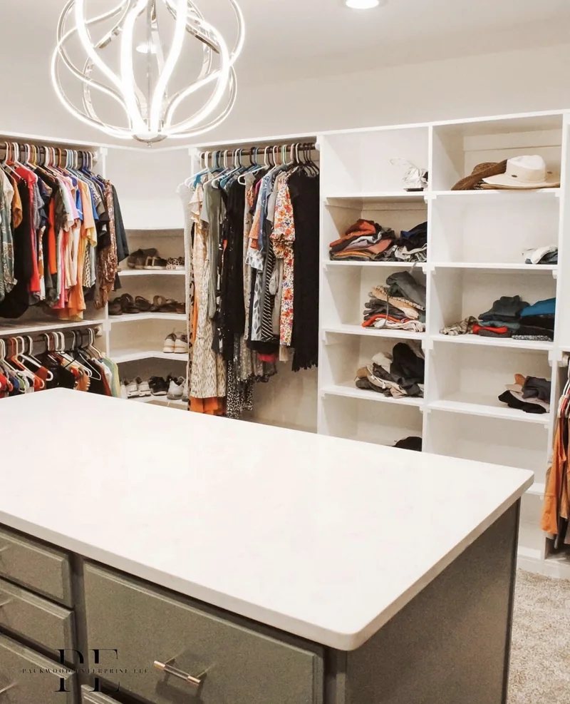 Walk-in closet with shelving, clothing and a central island