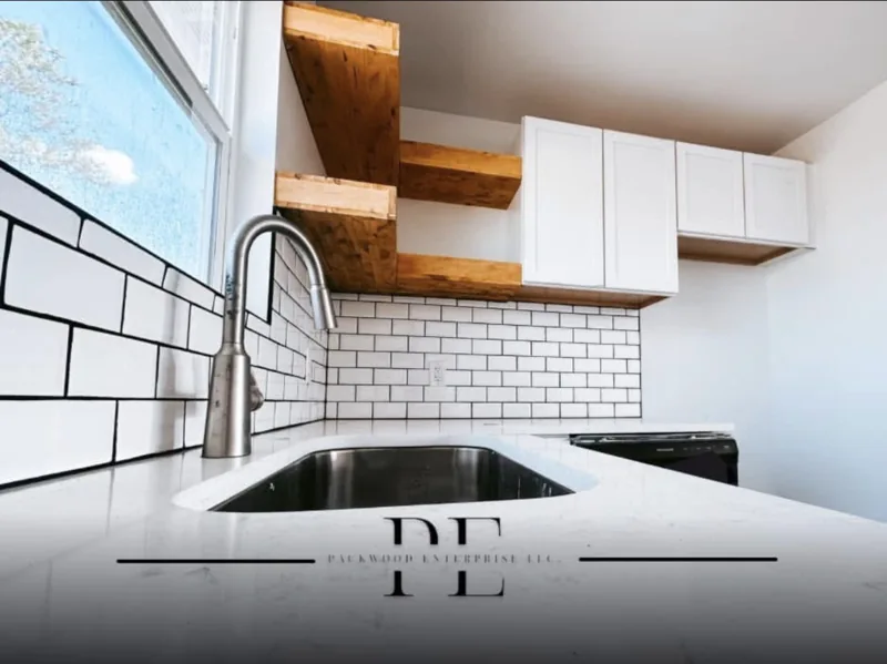 Kitchen sink with a tile backsplash, cabinets and wood shelving